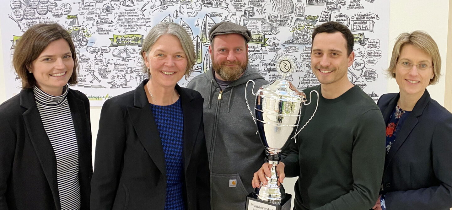 Stellvertretende Schulleiterin der BS 18 Anne Rauh-Wesseloh, Schulleiterin Wiebke Schuleit, Benedikt Fuss, Stefan Lütgert und Dr. Sandra Garbade mit dem Siegerpokal an der BS18.