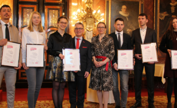 Drei junge Männer und drei junge Frauen stehen mit Urkunden in der Hand in einer Reihe. In Ihrer Mitte stehen der Präsident der Handwerkskammer, Hjalmar Stemmann und die Senatorin für Schule und Berufsbildung Ksenija Bekeris. Der Hintergrund ist der prunkvolle Bürgermeistersaal im Hamburger Rathaus.